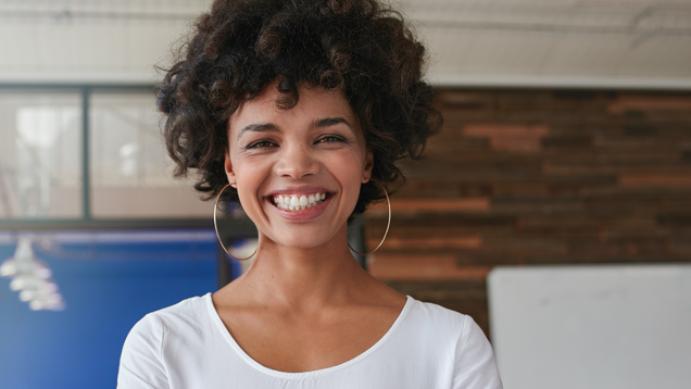 Smiling young woman standing with her arms crossed in office